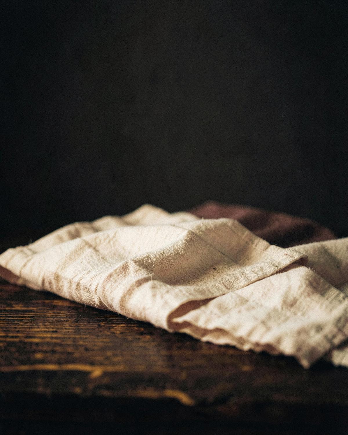 Ivory linen on dark timber, editorial still life